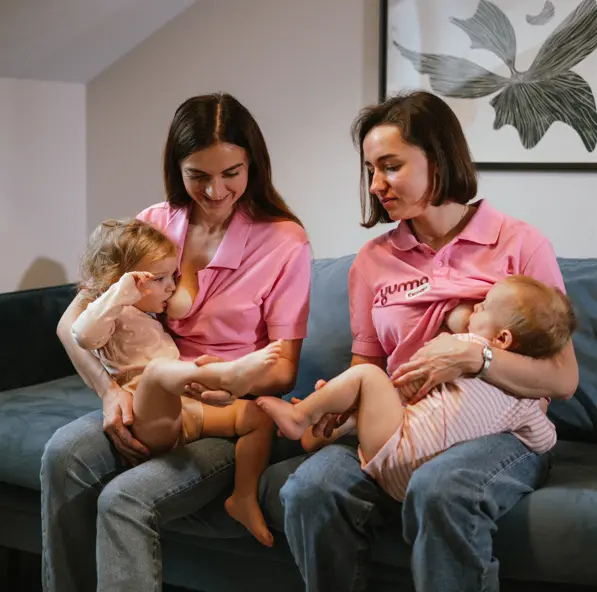 Дві мами годують немовлят грудним молоком, сидячи на дивані вдома — підтримка грудного вигодовування та турбота про дітей